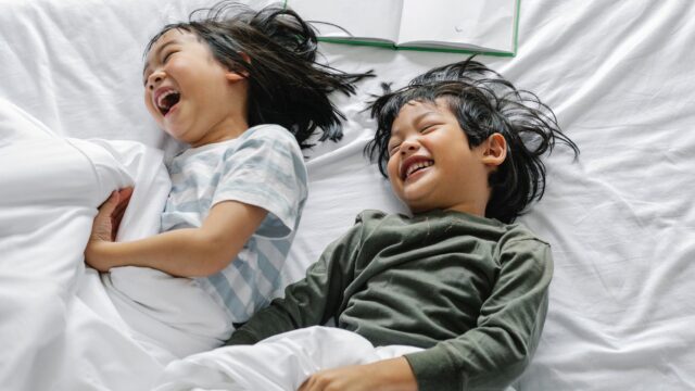 cheerful asian kids having fun in bed